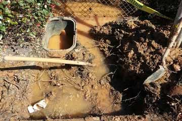 Water leak repair on the side of a home's backyard fence.